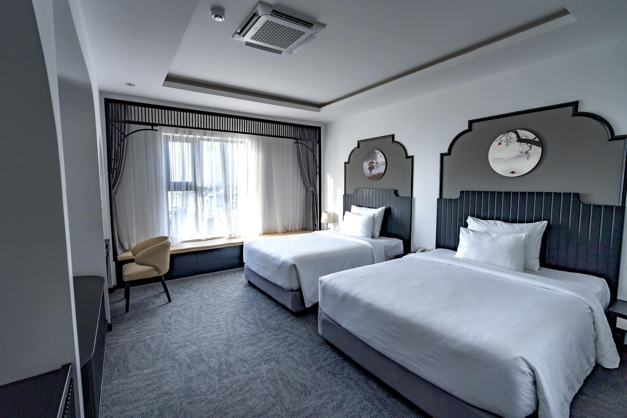 Spacious hotel room featuring two twin beds, elegant decor, and stylish furnishings.